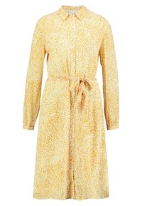 Žluté šaty s dlouhými rukávy, zapínání na knoflíky a stahovacím páskem v pase. Jsou zdobeny vzorem listů na lehké látce.