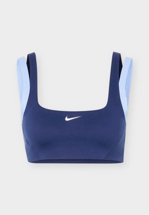 Tengerészkék sportmelltartó világoskék dupla pántokkal és fehér Nike logóval a mellkas közepén.