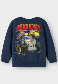 Felpa navy con grafica colorata di camion mostro con il testo "LE RUOTE DEL SOCCORSO REGNANO!". Le maniche e l'orlo a coste aggiungono una texture interessante.