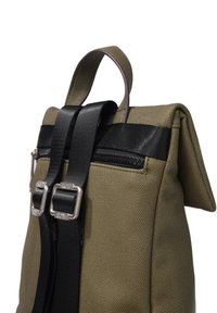Mochila de lona en verde oliva con tirantes negros y herrajes plateados. Cuenta con un bolsillo con cremallera y un diseño de parte superior plegada.