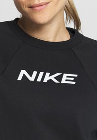 Persona vistiendo un sudadera negra de Nike con un logo blanco, mostrando una vista parcial de la parte inferior del rostro, el cuello y la parte superior del torso.