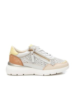 Zapatilla blanca con acentos beige y amarillos, laterales perforados, cordones blancos, detalle de cremallera dorada y suela blanca gruesa.