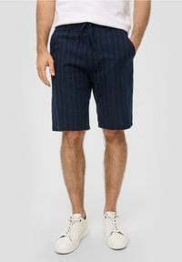 Marineblauwe gestreepte shorts van lichtgewicht stof, met een elastische tailleband met koord en zijzakken, gecombineerd met witte sneakers.