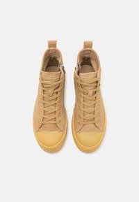 Baskets montantes beiges en suède, avec un design à lacets, un embout en caoutchouc et une semelle en caoutchouc texturé. Équipées d'une fermeture éclair et d'une boucle pour un enfilage facile.