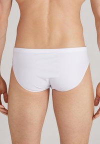 Weiße Schwimmbrief mit glatter Textur und enganliegendem Sitz, mit minimalen Nähten und einem schlichten Design ohne Muster oder Akzente.
