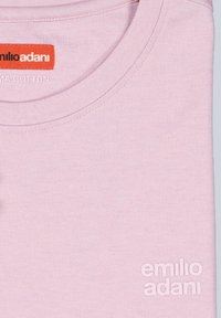 Helles rosa T-Shirt aus Baumwolle, mit rundem Kragen, strukturiertem Oberflächen sowie geprägtem Markenlogo in der unteren rechten Ecke.
