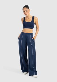 Navyblauer Sport-BH und weite Hose mit weißen seitlichen Streifen. Weicher Stoff, elastischer Bund und lässige Passform für optimalen Komfort.