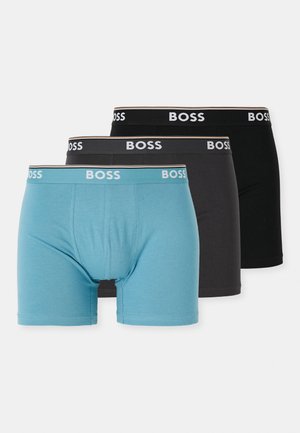 Three men's boxer shorts: one in light blue, one in dark gray, and one in black. Each features a wide black waistband with "BOSS" logo.