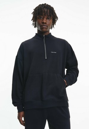Pullover de cremallera negra fabricado en mezcla de algodón. Presenta un cuello alto, bolsillo frontal y logo bordado en el pecho. Corte relajado.