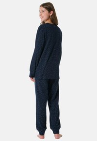 Navy nachthemden set bestaande uit een langemouwen top en broek, versierd met rood-witte stippen; zachte stof en een relaxte pasvorm.