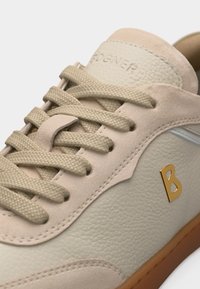 Μπεζ δερμάτινο αθλητικό παπούτσι με ανάγλυκα κορδόνια, σουέντ λεπτομέρειες, χρυσό λογότυπο "B" στο πλάι και καφέ λαστιχένια σόλα.