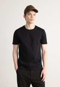 Black cotton t-shirt with a crew neckline, short sleeves, and a smooth texture, paired with a brown cap featuring the word "BOSS" embroidered.
