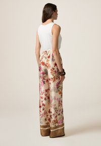 Satin broeken met een floral patroon en een elastische tailleband in natuurlijke tinten, met levendige roze en oranje bloemen, en een bruine zoomafwerking.