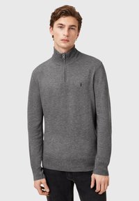 Grauer Pullover mit halbem Reißverschluss am Kragen, langen Ärmeln und gerippten Bündchen. Ein kleines Logo ist auf der linken Brustseite angebracht. Weiche Textur.