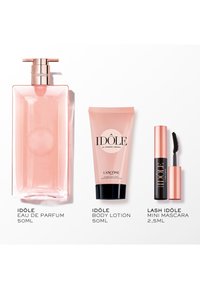 Różowa szklana buteleczka perfum, dopasowana różowa tuba z balsamem oraz mini tusz do rzęs w eleganckim czarno-rose złotym opakowaniu. Etykiety z tekstem wyświetlane poniżej przedmiotów.