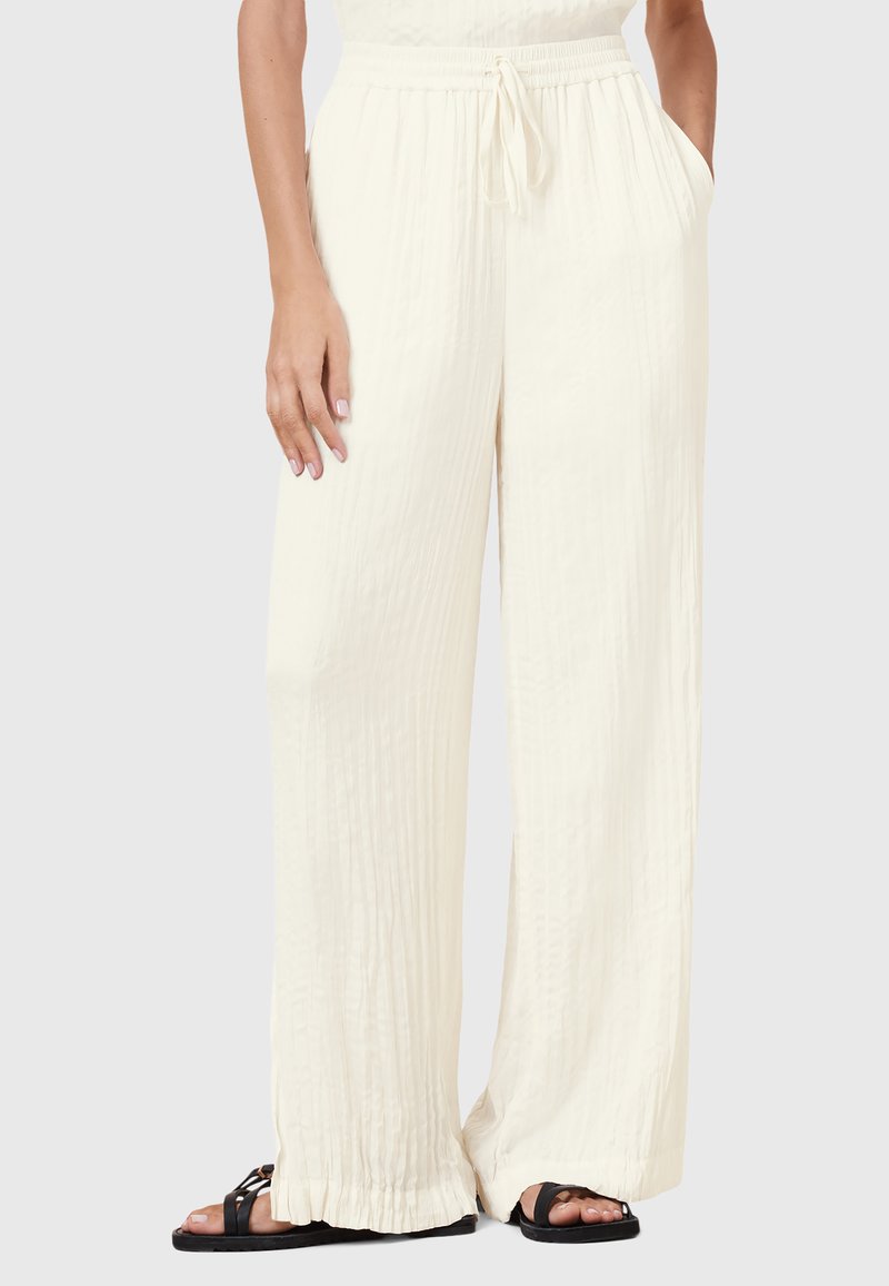 Crème wijde broek van een textuurstof, met een elastische tailleband en een trekkoord, en zijzakken; gecombineerd met zwarte sandalen.