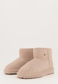 Beige suede enkellaarsjes met een ronde neus, decoratieve stiksels en een logo-accent aan de zijkant. Getextureerde rubberen zool met profiel.