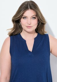 Top senza maniche blu navy con scollo a V leggermente pronunciato, realizzato in tessuto morbido, con dettagli testurizzati sottili e una vestibilità rilassata.
