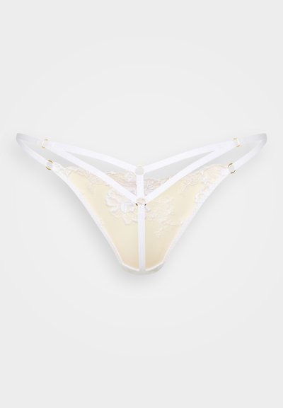 Csipkés tangabugyi lágy sárgában, fehér elasztikus pántokkal. Virágmintás anyag, arany színű fém díszítésekkel és V-alakú dizájnnal.