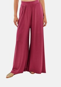 Kalhoty s širokými nohavicemi v tmavě burgundské barvě, vyrobené z měkké látky. Mají volný střih a elastický pas. Hladký povrch, bez vzorů.