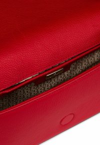 Sac en cuir rouge avec une surface texturée, un design plat et un intérieur en tissu à motifs avec un détail de fermeture métallique.