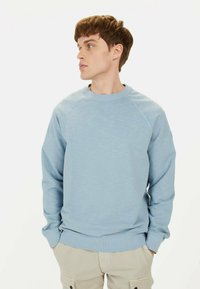 Hellblaues Sweatshirt mit strukturierter Oberfläche, rundem Ausschnitt und Raglanärmeln. Die Bündchen und der Saum sind gerippt für zusätzlichen Detail.