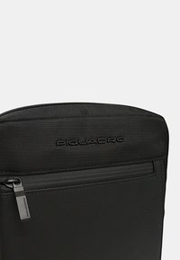 Pochette nera con zip, realizzata in nylon testurizzato, con una sezione inferiore liscia e logo a marchio in lettera in rilievo.