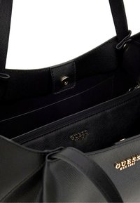 Borsa tote nera in pelle con superficie testurizzata, dotata di una tasca con zip, accessori in oro e logo impresso all'interno.
