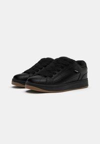 Sneaker in pelle nera con tomaia texturizzata, linguetta imbottita e spesse stringhe nere. Presenta una suola in gomma color gomma a contrasto e accenti laterali.