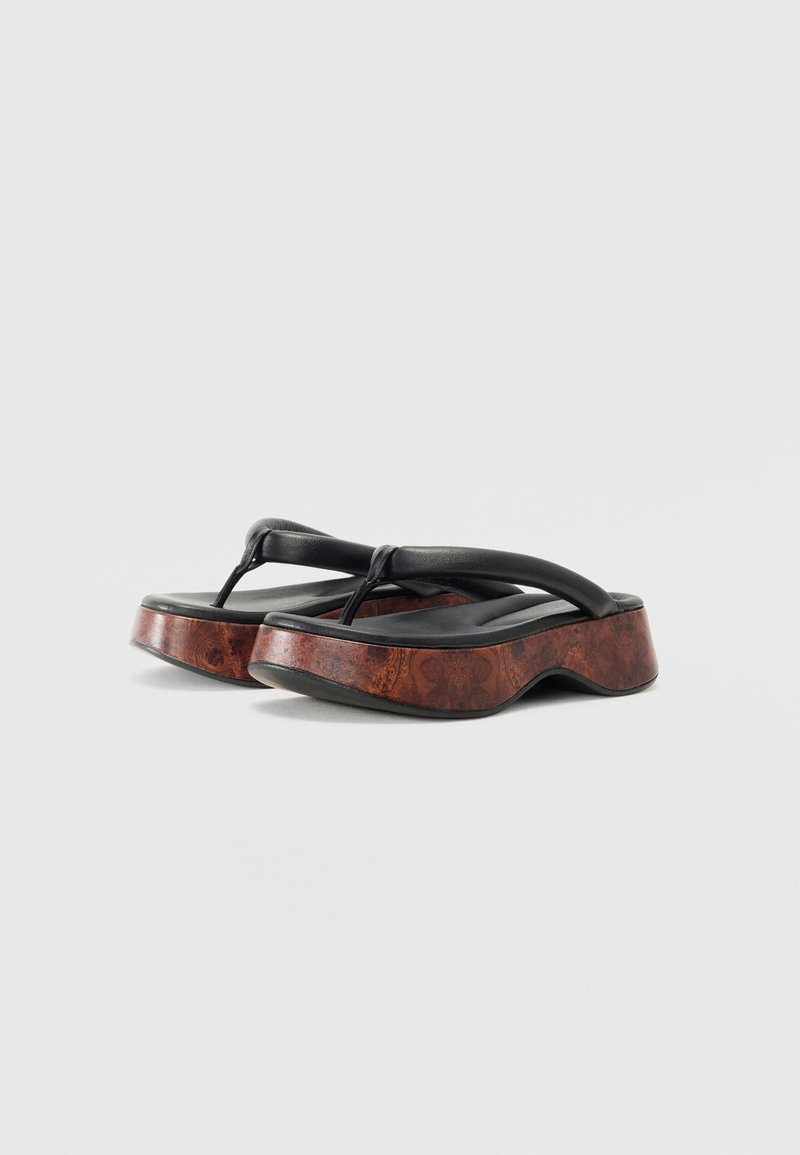 Sandalias de flip-flop de cuero negro con un grueso tacón marrón con patrón y un diseño de suela curvada. Correas flexibles para un ajuste seguro.