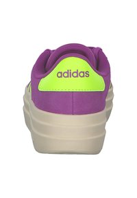 Paarse sneaker met neongroene accenten en het "adidas" logo op de hiel. Heeft een gestructureerde bovenkant en een crèmekleurige rubberen zool.