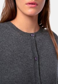 Grauer Strickcardigan mit rundem Ausschnitt, vorn mit Knöpfen und lila Akzenten sowie weicher Textur.