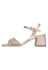Sandal con tacco a blocco in metallo dorato chiaro, con punta aperta. Presenta fibbie incrociate decorate con perline decorative. Cinturino alla caviglia regolabile.