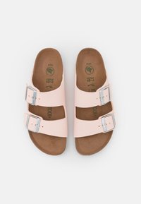 Sandali rosa chiaro con due cinturini, fibbie argentate e una soletta marrone. La parte superiore è in materiale liscio; la soletta presenta una texture naturale.
