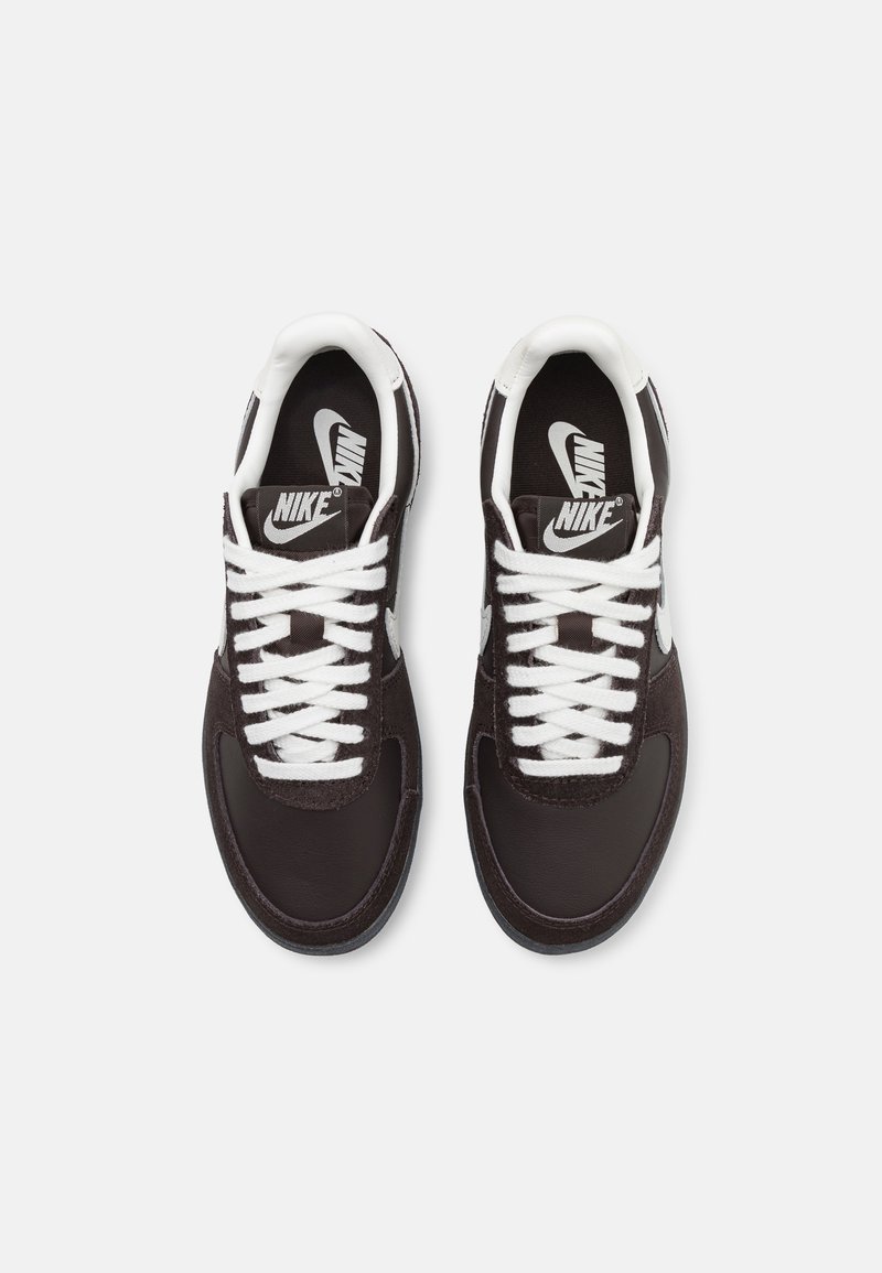 Crne tenisice s bijelim vezicama, izrađene od glatke kože i teksturirane suede gornje strane, okrugli vrh i istaknuti Nike logo na jeziku.