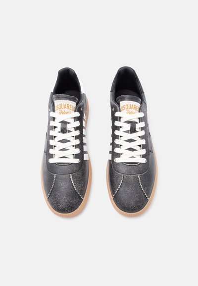 Paire de baskets en cuir noir et blanc avec des lacets blancs, des semelles en gomme, et une languette de marque portant l'inscription « Dsquared2 Rebels » sur un fond uni.