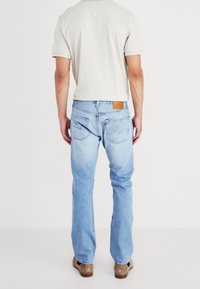 Ljusblå denimjeans med rak benmodell, lädermärke på baksidan och subtila sömnadsdetaljer. Bär med en ljus randig t-shirt.