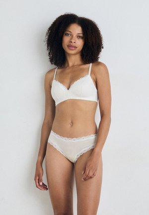 Witte kanten bh met een golvende rand en dunne bandjes, gecombineerd met bijpassende slipjes met kantafwerking. Glad, lichtgewicht stof met een delicate textuur.