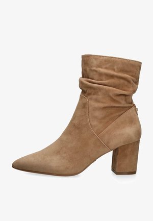 Bottine en daim beige avec tige ample, bout pointu et talon bloc.