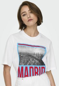 Witte katoenen T-shirt met een grafische print van Madrid met rode en blauwe accenten, een ronde halslijn en korte mouwen.