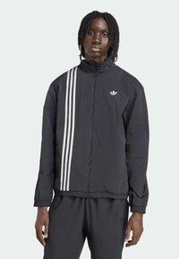 Black windbreaker jacket with a high collar, featuring white three-stripe design on the left side and a small logo on the chest.