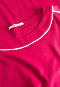 Feraud Paris Hemd aus leuchtend pinkem Stoff mit weicher Textur, ausgestattet mit einem weißen Paspelkragen und einem Etikett nahe dem Halsausschnitt.