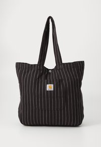 Bolsa de lona negra con rayas verticales blancas, dos asas largas y un bolsillo frontal con una etiqueta de logo cuadrada.