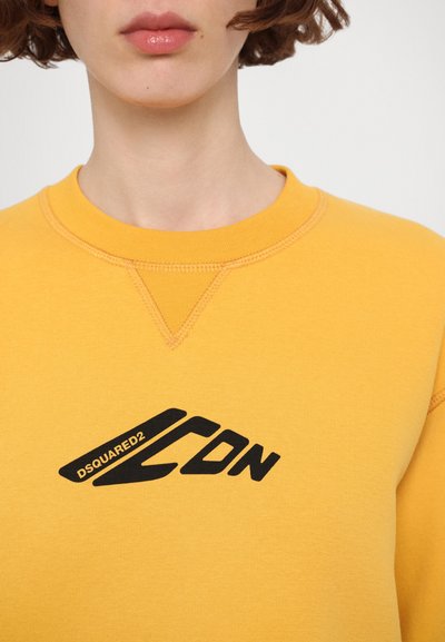 Gul genser med ribbestrikket hals, med svart logo-print "DSQUARED2 ICON" på brystet. Materialet ser mykt og glatt ut.