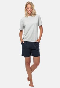 Lichtgrijs katoenen t-shirt met korte mouwen, gecombineerd met marineblauwe shorts. Beide kledingstukken hebben een comfortabele pasvorm en de shorts hebben zakken.