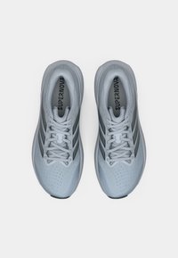 Ανοιχτό γκρι παπούτσια τρεξίματος με επάνω μέρος από δίχτυ, τρεις σκουρόγκρινες ρίγες, στρογγυλή μύτη, επενδεδυμένος γιακάς και κορδόνια. Σημαντική διάτρητη υφή στη μύτη.