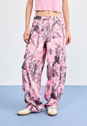 Pantalons cargo roses avec un motif de feuilles et de branches, fabriqués en tissu léger. Présentent des poches et un design ample.