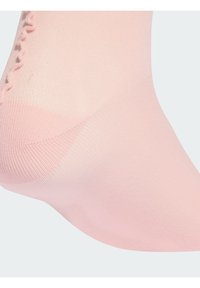 Svetloružová ponožka vyrobená z hladkej tkaniny s volánovým horným okrajom, s vystuženou špičkou a pätou pre odolnosť.