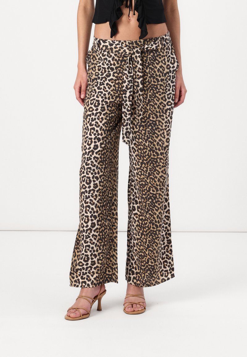 Leopardenmuster weite Hosen aus beige-braunem Stoff, mit einer Krawatte auf der Taille und glatter Textur. Kombiniert mit hautfarbenen Riemchenschuhen.