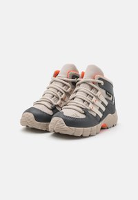 Beige and dark gray hiking shoes with mesh upper, rubber toe cap, and orange accents. Features laces and textured outsole for grip.